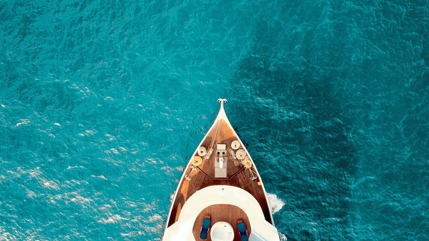 The bow of a boat gliding over turquoise water in the Maldives
